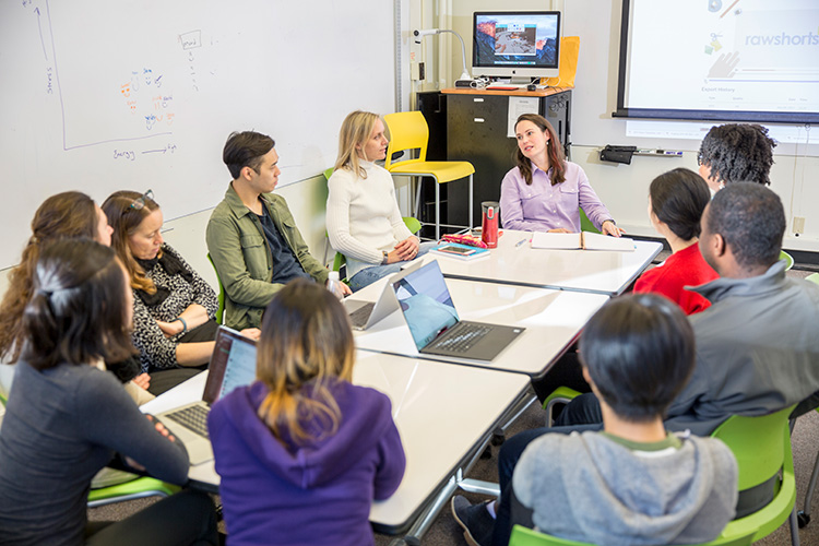 Humanities Academic Services advisor speaking with a group of students around a table.
