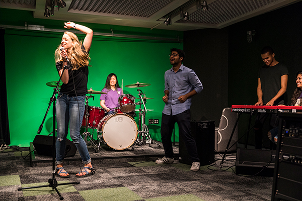 Students using the sound lab, singing and playing drums