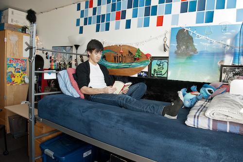 A student sitting in a bed reading a book