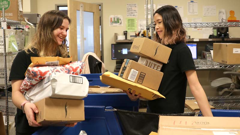 Student workers carry packages in the mailroom