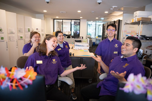 Student employees smiling at a desk