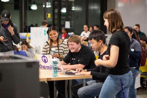 Students smiling on a computer at The MILL